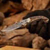 Handmade Damascus steel folding pocket knife with stag horn handle held in hand, gift for him.