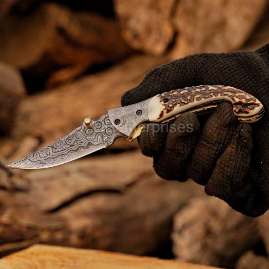 Handmade Damascus steel folding pocket knife with stag horn handle held in hand, gift for him.
