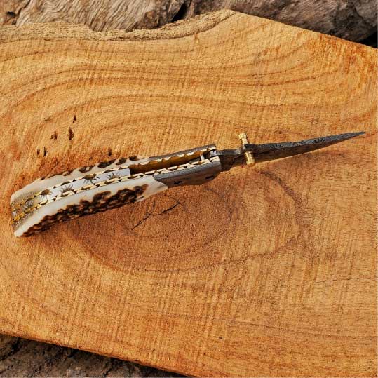 Top view of handmade Damascus folding knife with stag horn handle.