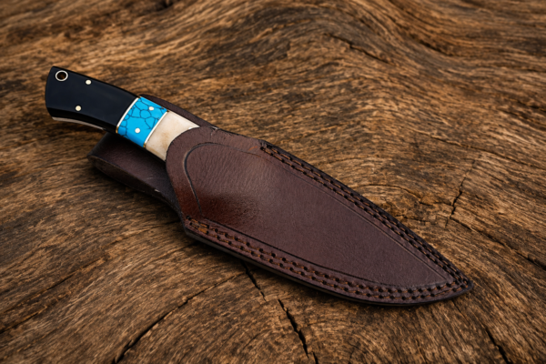Custom Damascus hunting knife with leather sheath on wooden background