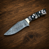 Custom Damascus steel knife with resin handle on wooden table