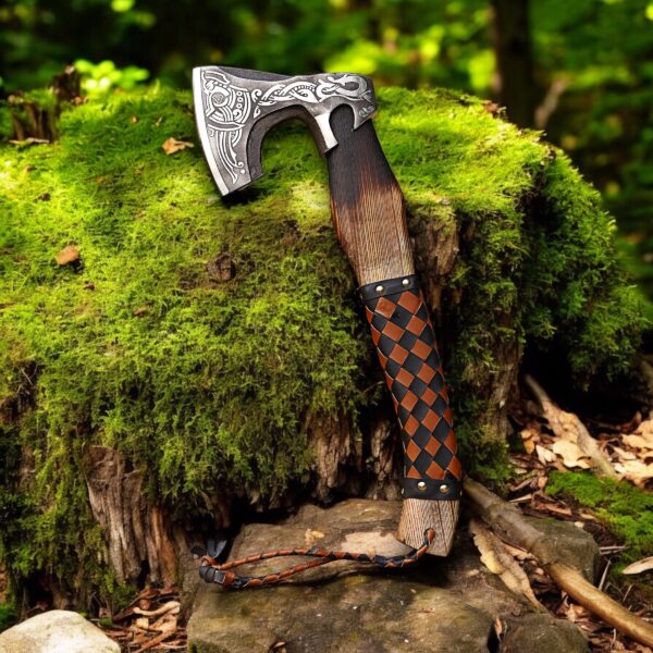 Handmade camping axe standing on tree stump in forest
