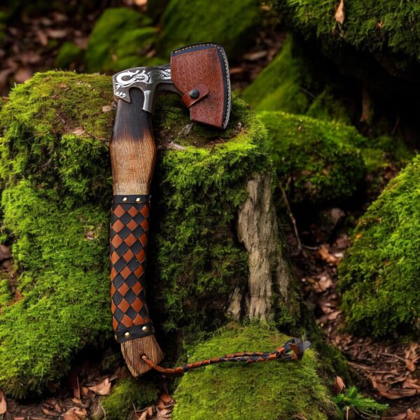 Handmade Viking axe with leather sheath placed on mossy forest ground