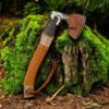 Handmade Viking axe with leather sheath and engraved Nordic blade on mossy wood background