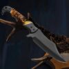Handmade carbon steel hunting knife with fire bone handle displayed on tree branch outdoors
