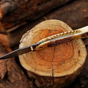 Side view of handmade Damascus folding knife with camel bone handle and brass details