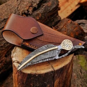 Damascus steel folding knife displayed over a brown leather sheath