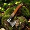 Viking-style axe with leather-wrapped handle displayed vertically on a moss-covered rock in the forest