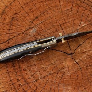 Handmade Damascus folding knife with black handle on wooden surface