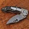 Open handmade Damascus folding knife with black handle